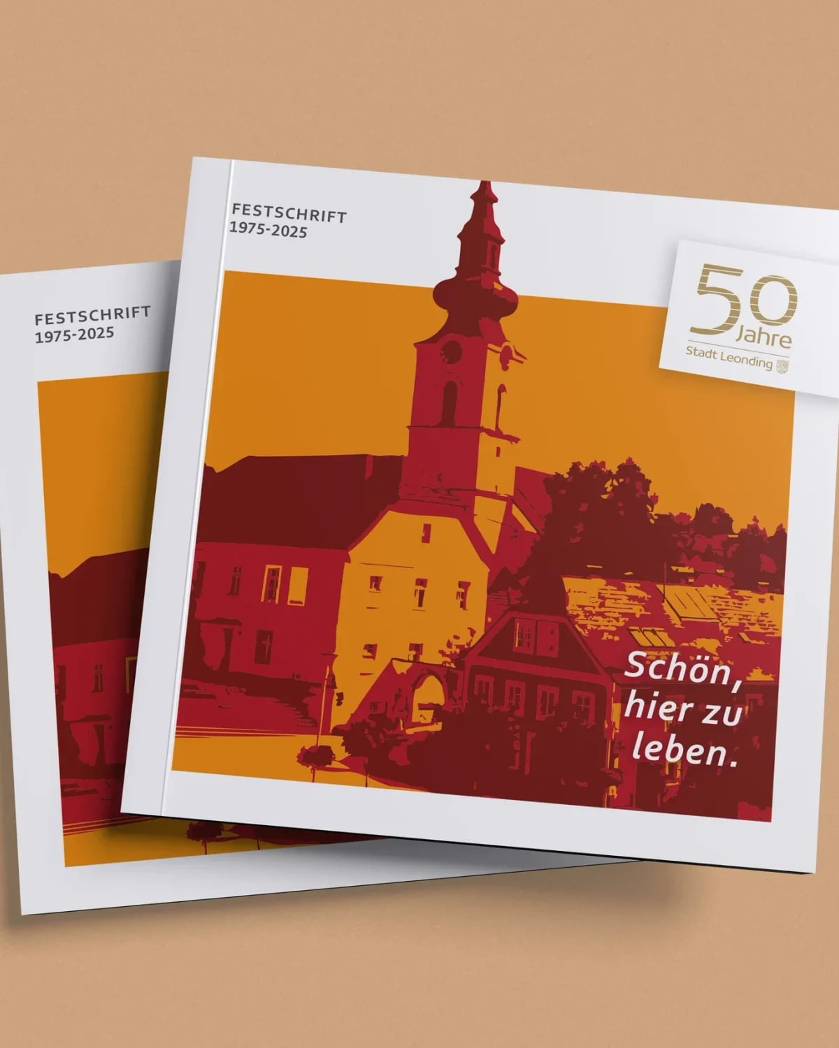 Festschrift „50 Jahre Stadt Leonding" 1975–2025 – quadratische Broschüre mit illustriertem Kirchturm in Rot-Orange und Slogan „Schön, hier zu leben."